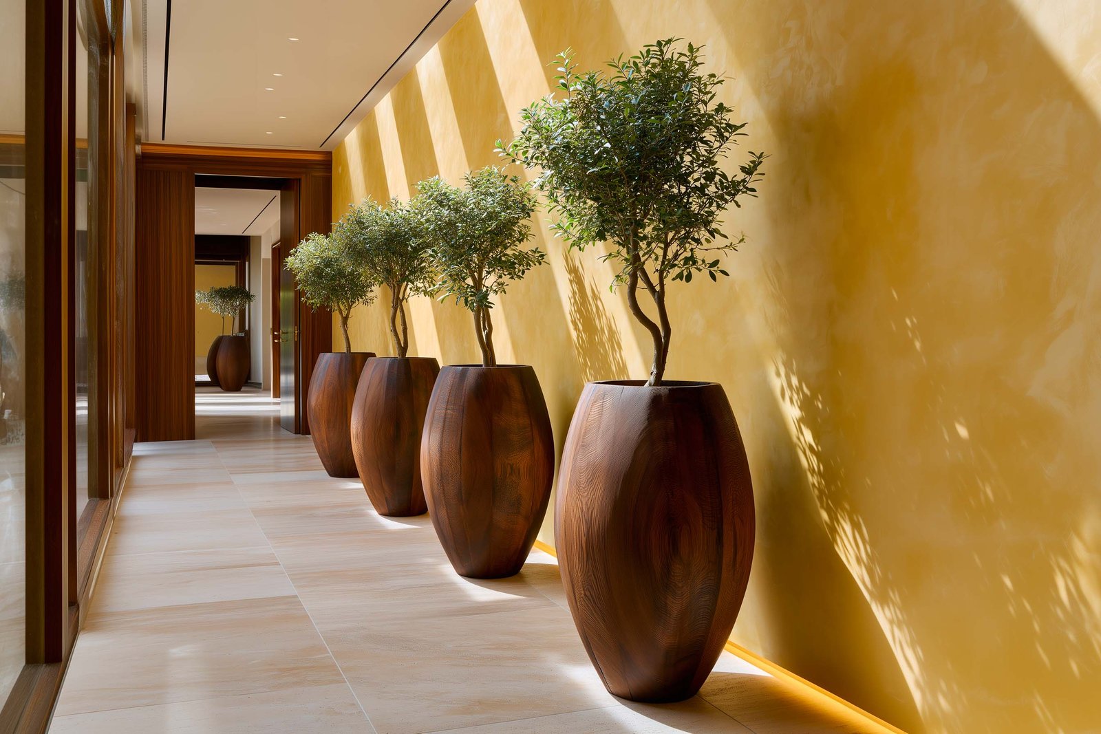 Rythme et répétition — succession de cinq grands pots Lignum™ en noyer fumé alignés contre un mur en stucco lustro, jeunes Laurus nobilis en port libre, couloir contemporain à Roquebrune-Cap-Martin, Paracelsus Gardens™