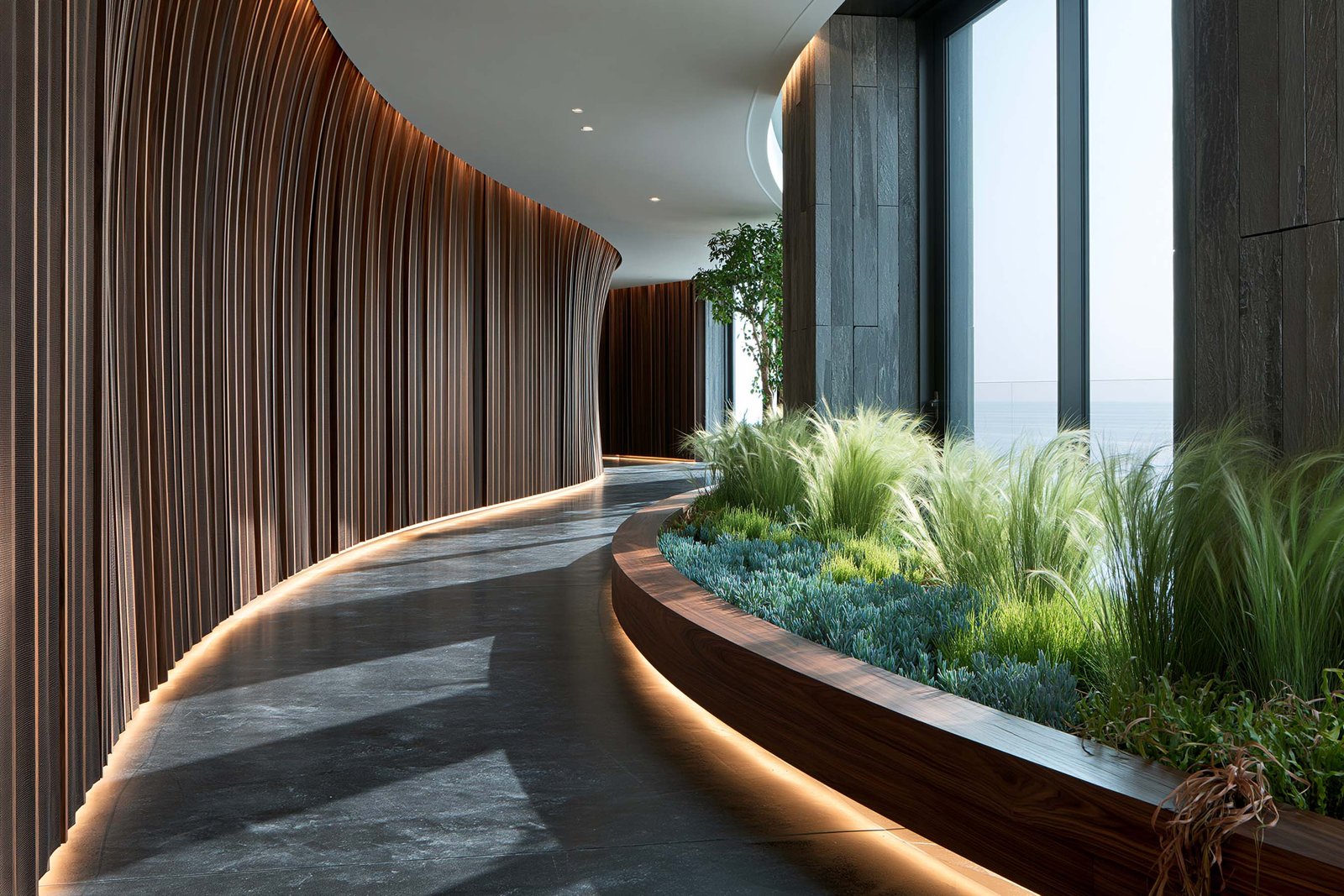 Seuil — relâchement vers la lumière : couloir sinueux d’un spa à Monaco, partition SylvaVeil™ courbe en lames verticales de noyer fumé et sol en micro-béton anthracite, bac Lignum™ courbe portant Stipa tenuissima, Senecio serpens et Carex testacea, baies vitrées sur horizon Méditerranée, LED 2700K cachée, Paracelsus Gardens™