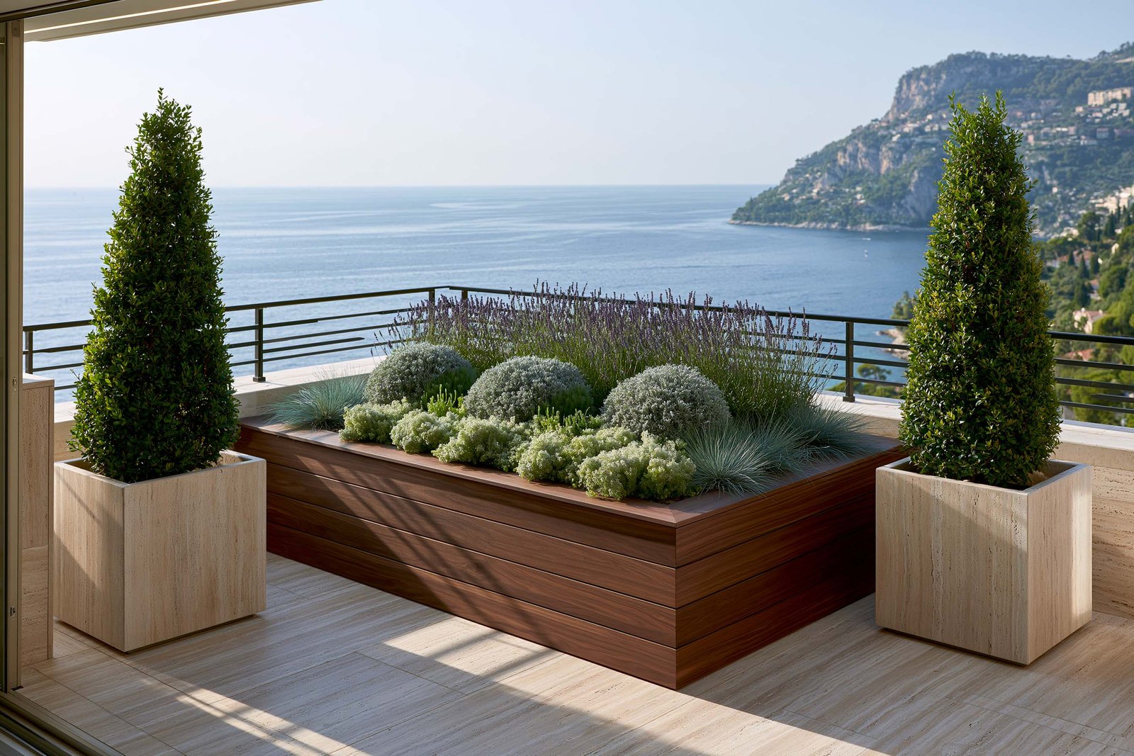Cadrage et perspective — balcon contemporain d’un appartement à Beaulieu-sur-Mer en milieu de matinée, parapet et sol en travertin clair warm honey, deux Laurus nobilis en topiaires colonnes pyramidales dans des pots cube en travertin clair encadrent la vue Méditerranée, long planter Lignum™ Block en noyer fumé contre le parapet portant Lavandula angustifolia en arrière-plan, Santolina chamaecyparissus et Helichrysum italicum en masses argentées et Festuca glauca en touffes blue-grey, calme horizon Méditerranée avec cap rocheux à distance, Paracelsus Gardens™