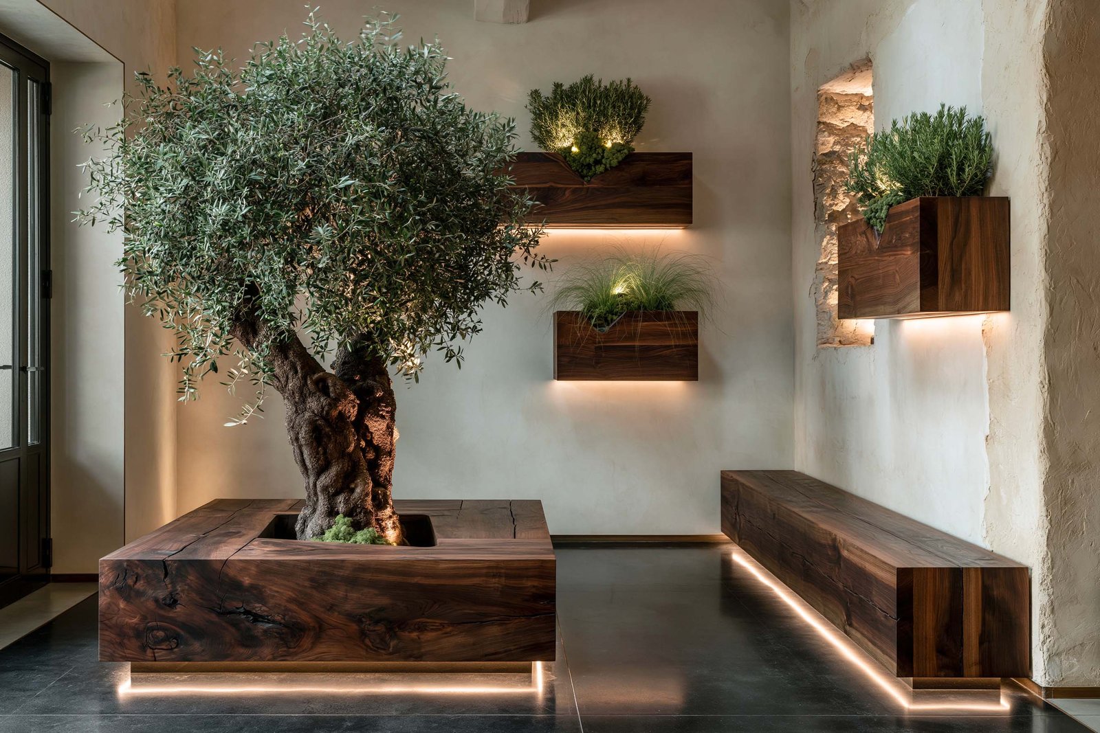 Hall d’entrée d’un restaurant gastronomique à Saint-Jean-Cap-Ferrat, composition de modules Lignum Block Dark en noyer fumé d’où émergent olivier, romarin et graminée, halo LED chaude au sol.